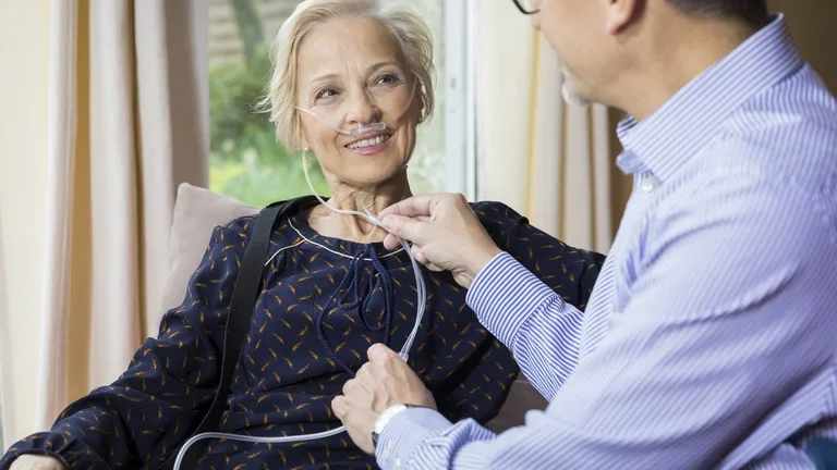 Homem ajustando o aparelho de oxigênio portátil de uma mulher