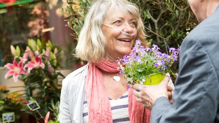Mulher recebendo flores e utilizando oxigênio portátil 