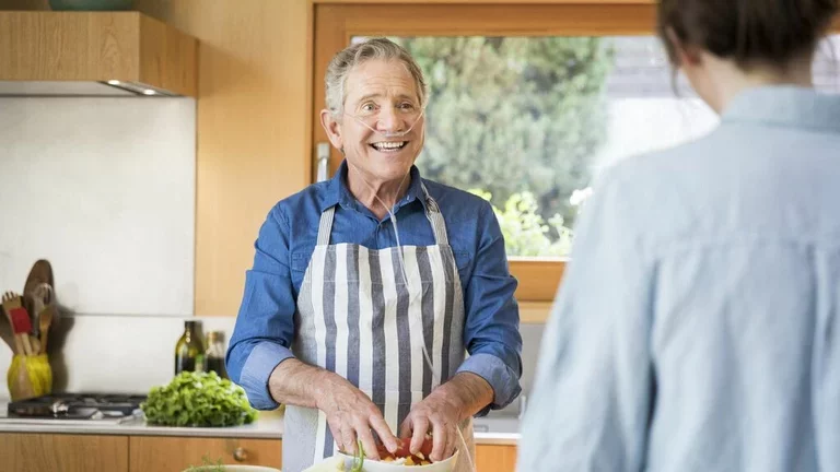 Homem cozinhando usando oxigênio portátil para DPOC