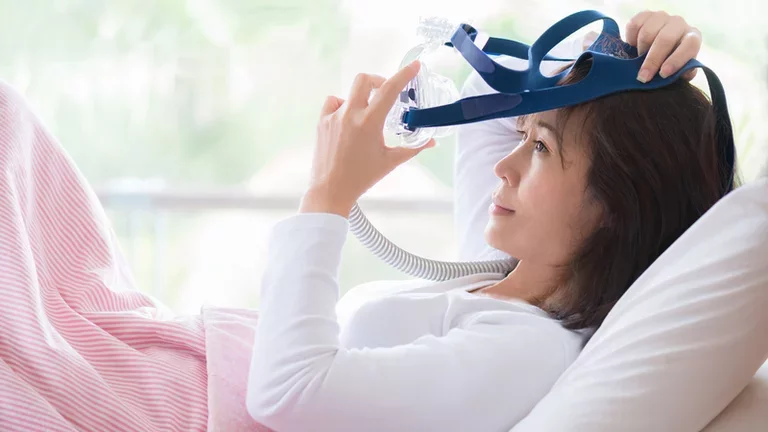 Mulher colocando máscara para terapia com CPAP