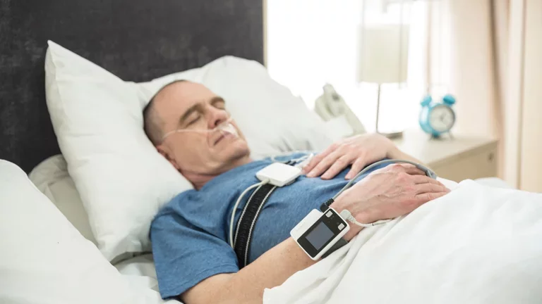 Homem realizando exame domiciliar de polissonografia para detectar apneia do sono 