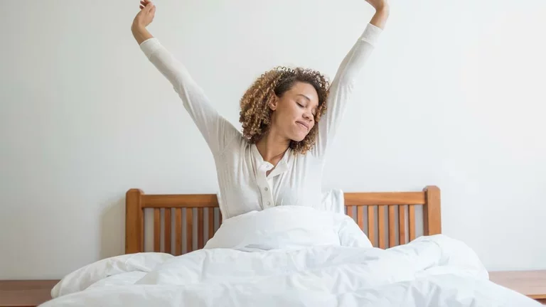 Mulher deitada na cama bocejando depois de uma noite mal dormida.