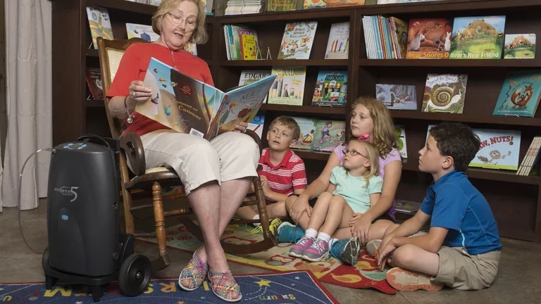 Mulher com concentrador de oxigênio lendo um livro de história para crianças