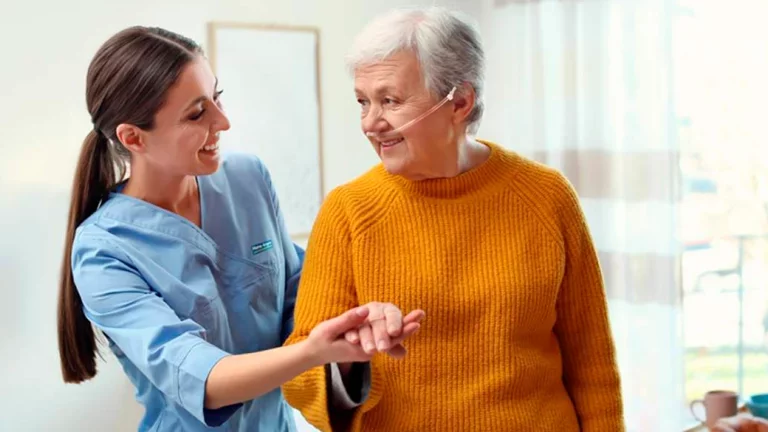 Profissional auxiliando mulher idosa em uso de oxigênio com catéter nasal