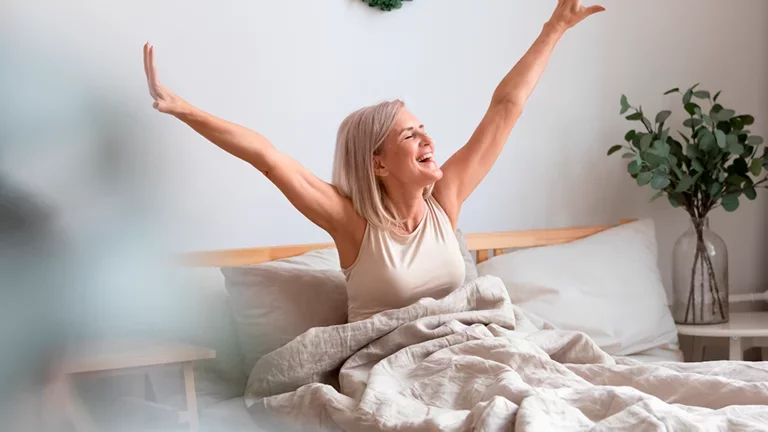 Mulher acordando feliz em sua cama