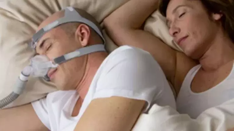 Homem usando a Máscara Nasal Respireo SOFT ALMS para dormir ao lado da sua esposa