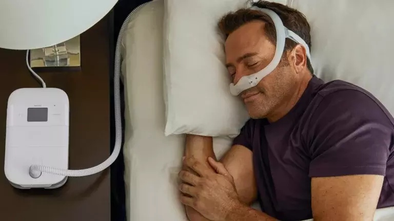 Homem dormindo na cama usando CPAP nasal 