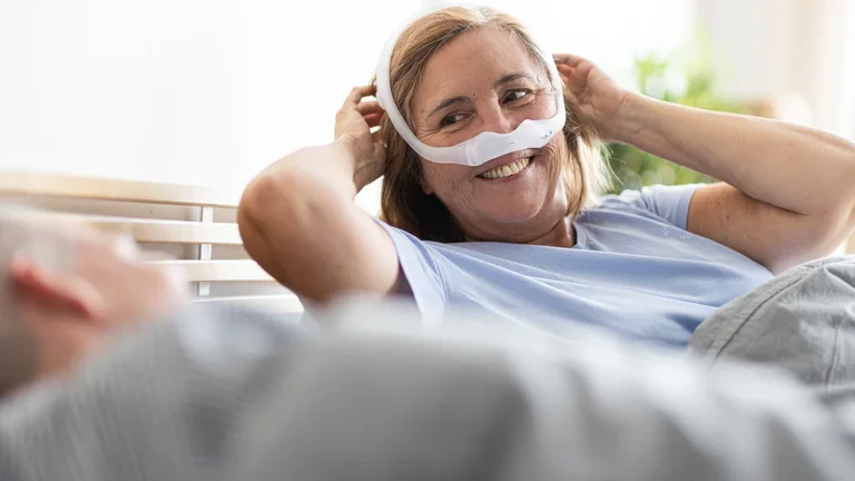 Mulher com apneia do sono acordando feliz com sua máscara DreamWear