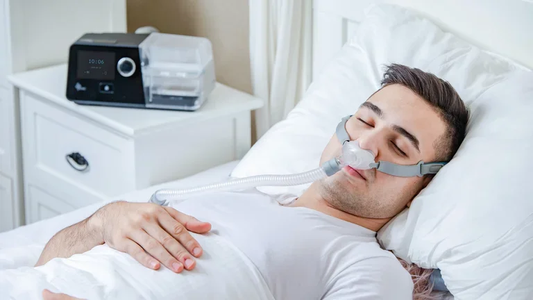 Homem deitado em sua cama com CPAP confortável