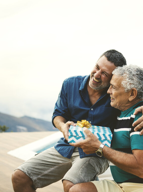 Imagem de pai presenteando filho a beira da piscina