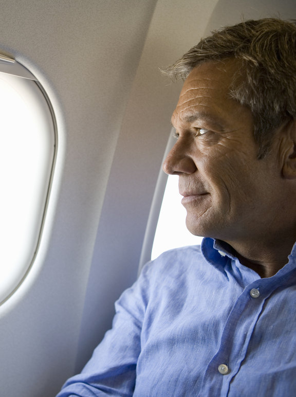 Homem viajando e olhando pela janela do avião