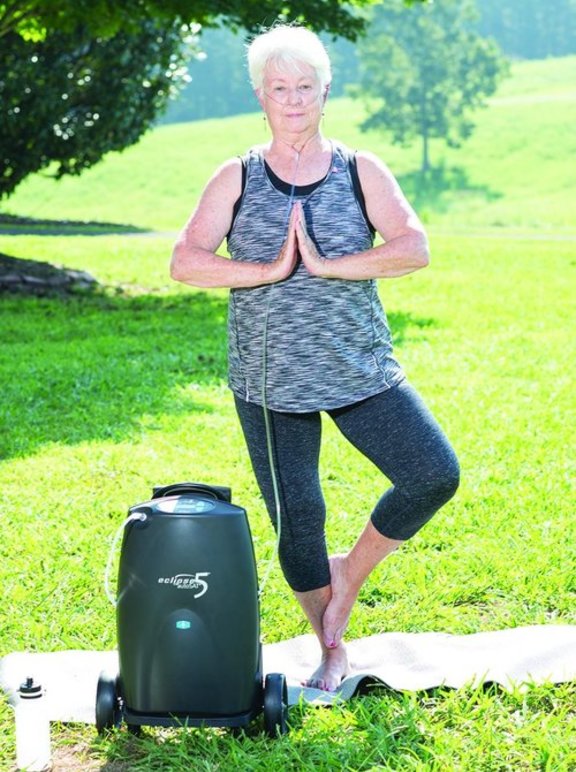 Mulher com oxigênio transportável fazendo yoga