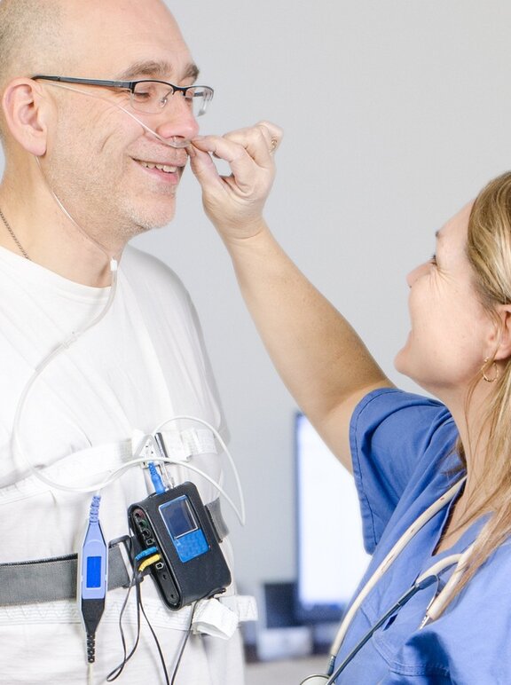 Profissional conectando o equipamento de polissonografia domiciliar