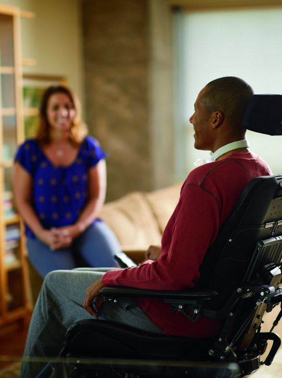 Homem na cadeira de rodas e submetido a ventilação mecânica conversando com esposa