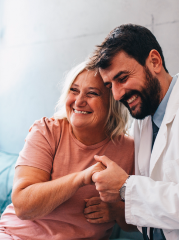 Profissional com paciente em atendimento abraçando-a e feliz