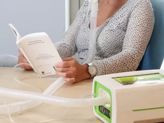 Mulher lendo enquanto usa aparelho de ventilação mecânica EO-150