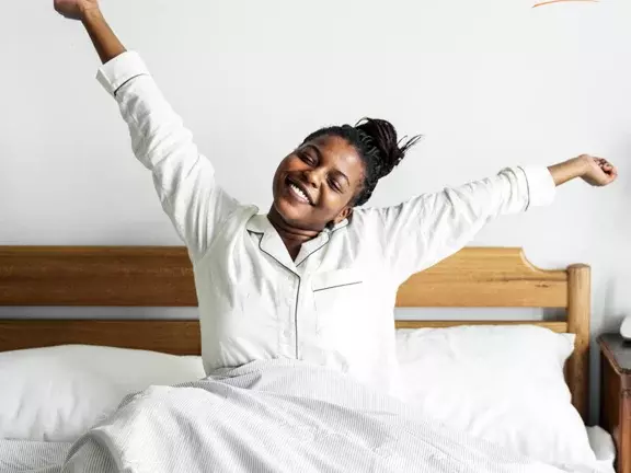 Mulher acordando feliz após uma boa noite de sono