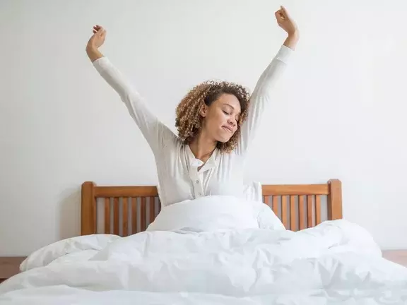 Mulher deitada na cama bocejando depois de uma noite mal dormida.