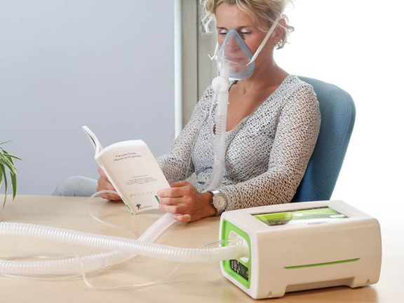 Mulher em ventilação mecânica não invasiva lendo um livro