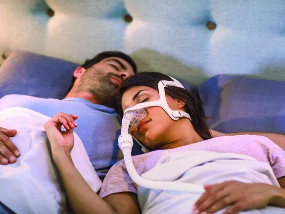 Homem e mulher dormindo com CPAP em casa
