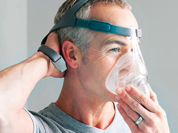 Homem colocando a máscara de ventilação mecânica não invasiva