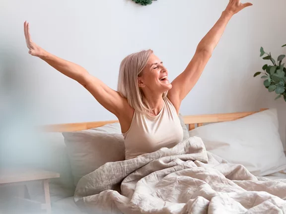 Mulher acordando feliz em sua cama
