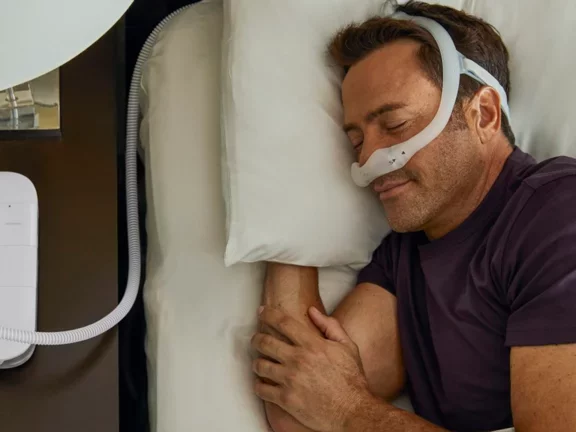 Homem dormindo na cama usando CPAP nasal 