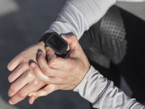 Homem avaliando seu smartwatch após acordar sentado na cama
