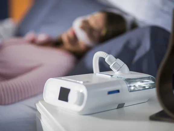 Mulher dormindo com seu CPAP para o tratamento da apneia do sono e ronco