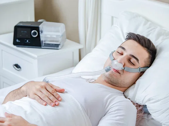 Homem deitado em sua cama com CPAP confortável