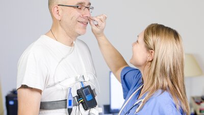 Profissional conectando o equipamento de polissonografia domiciliar