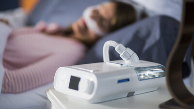 Mulher dormindo com seu CPAP para o tratamento da apneia do sono e ronco