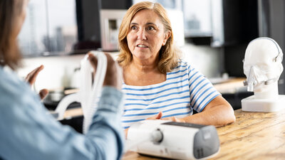 Mulher testando o CPAP para apneia do sono com orientação profissional
