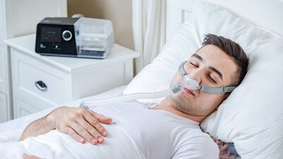 Homem deitado em sua cama com CPAP confortável