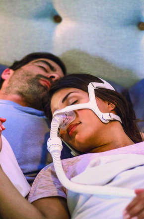 Homem e mulher dormindo com CPAP em casa