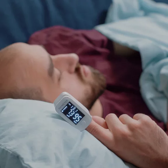 Homem deitado utilizando oxímetro de dedo