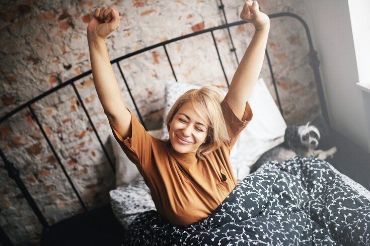 Mulher acordando feliz e disposta após uma boa noite de sono