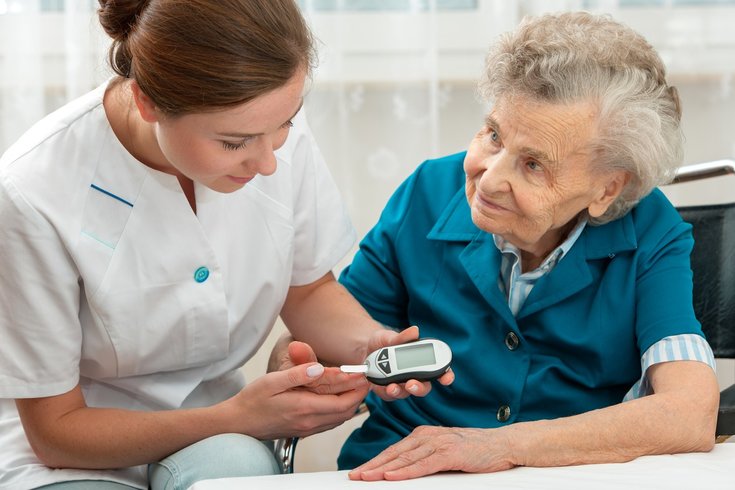 Enfermeira medindo a glicemia da paciente idosa
