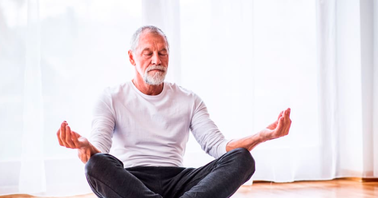 Homem idoso sentado no chão e meditando