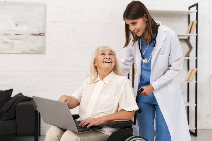 Profissional da saúde prestando assistência domiciliar a paciente por meio de seu notebook