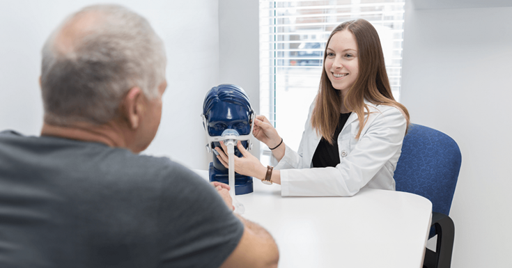 Consultora de Terapia Respiratória apresentando um modelo de máscara nasal ao paciente