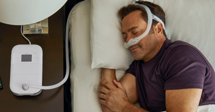 Homem dormindo na cama usando CPAP nasal 