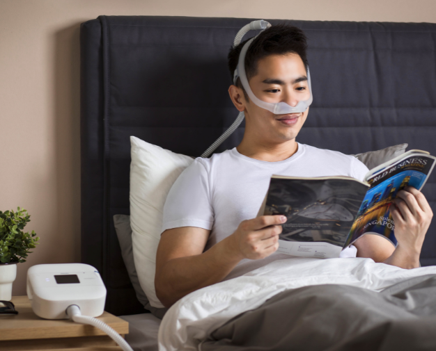 Homem em uso de cpap pronto para dormir em sua cama